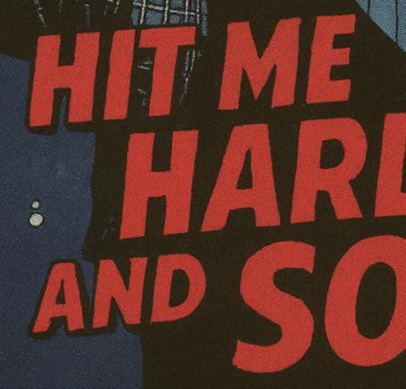 Pu&ograve; includere: Primo piano di un tessuto nero con le parole "HIT ME HARD AND SO" in grandi lettere rosse. Il testo ha un aspetto invecchiato e strutturato. Sul lato sinistro dell'immagine &egrave; visibile una grafica blu e bianca.