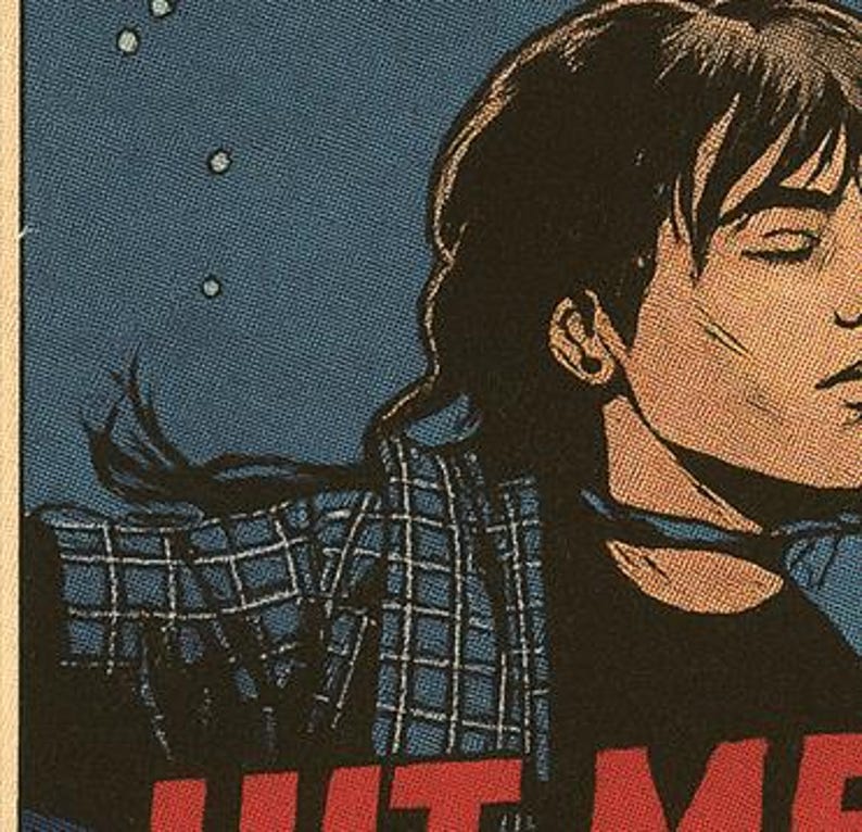 Pu&ograve; includere: Illustrazione in stile fumetto di una persona con capelli scuri e una camicia a quadri blu. La persona indossa una maglietta nera con le parole "HIT ME" in lettere rosse. Lo sfondo &egrave; blu scuro con puntini bianchi.