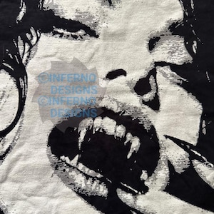 May include: Black and white graphic of a screaming face with sharp teeth. The image has a distressed, textured appearance, with the face's features boldly outlined against a light background. The design evokes a sense of horror.
