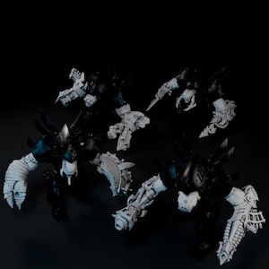 May include: Four detailed miniature figures, primarily black with gray and white accents, are arranged against a dark background. The figures have a mechanical or futuristic aesthetic, with intricate armor and weapon details. The overall theme suggests a science fiction or fantasy setting.