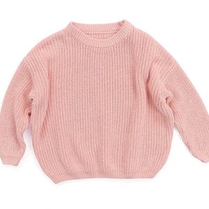 May include: A soft pink knitted sweater with a crew neck and long sleeves.