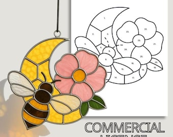 Puede incluir: Un atrapasoles de vidriera con una abeja, una luna creciente y una flor rosa. La abeja es marrón y amarilla, la luna es amarilla y la flor tiene pétalos rosas y un centro amarillo. Las palabras "COMMERCIAL LICENSE" están en la parte inferior.