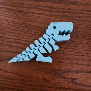 May include: A light blue plastic dinosaur skeleton toy. The dinosaur is in a walking pose with its mouth open.