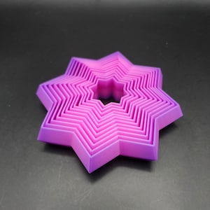 May include: A set of eight pink and purple star-shaped cookie cutters, nested together in decreasing size.