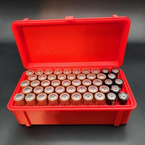 Puede incluir: Una caja de almacenamiento de pl&aacute;stico roja con una tapa con bisagras, llena de una variedad de bater&iacute;as AA. La caja est&aacute; dise&ntilde;ada para guardar y organizar las bater&iacute;as.