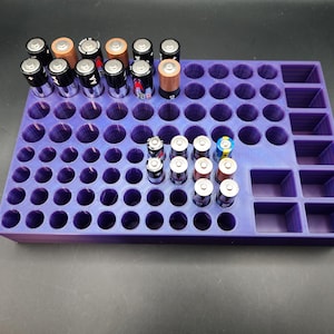 May include: A purple plastic battery organizer with 56 individual compartments for AA and AAA batteries. The organizer has a separate section with 12 larger compartments.