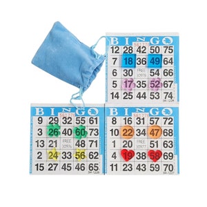 May include: Three blue bingo cards with a blue velvet bag. The cards have numbers 1-75 and the word "Bingo" at the top. Each card has a different set of numbers and a free space in the center. The cards are marked with colorful chips.