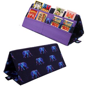 Pu&ograve; includere: Un organizer in tessuto viola con pi&ugrave; tasche, contenente carte da gioco vintage colorate. L'organizer &egrave; piegato, rivelando un tessuto blu navy con un motivo di elefanti blu e viola. Progettato per contenere ed esporre carte da gioco.