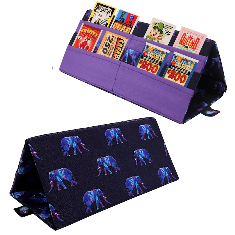 Pu&ograve; includere: Un organizer in tessuto viola con pi&ugrave; tasche, contenente carte da gioco vintage colorate. L'organizer &egrave; piegato, rivelando un tessuto blu navy con un motivo di elefanti blu e viola. Progettato per contenere ed esporre carte da gioco.
