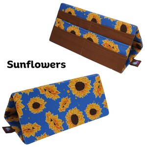 Pu&ograve; includere: Due organizer in tessuto con un motivo a girasoli su sfondo blu. Gli organizer hanno tasche marroni e sono etichettati "Sunflowers". I girasoli sono gialli e marroni.