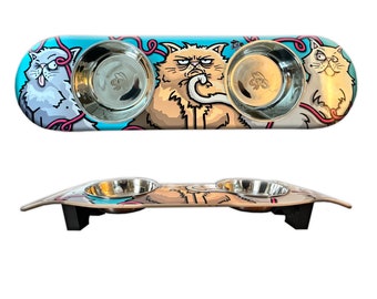 May include: A blue and white skateboard-shaped double cat food bowl with a cartoon image of three cats. The bowl is made of stainless steel and has a raised edge to prevent spills.