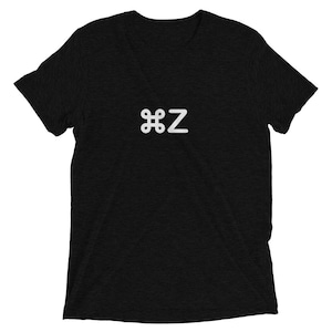 May include: Black t-shirt with a white graphic of a command symbol and the letter "Z". The shirt has short sleeves and a crew neck. The fabric has a textured appearance.