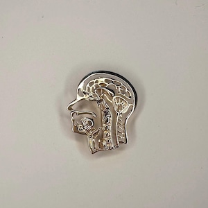 Könnte beinhalten: Eine goldfarbene anatomische Anstecknadel, die ein Seitenprofil eines menschlichen Kopfes zeigt und Gehirn, Rachen und andere innere Strukturen darstellt. Die Nadel hat einen schwarzen Rand und ist vor einem schlichten weißen Hintergrund platziert.