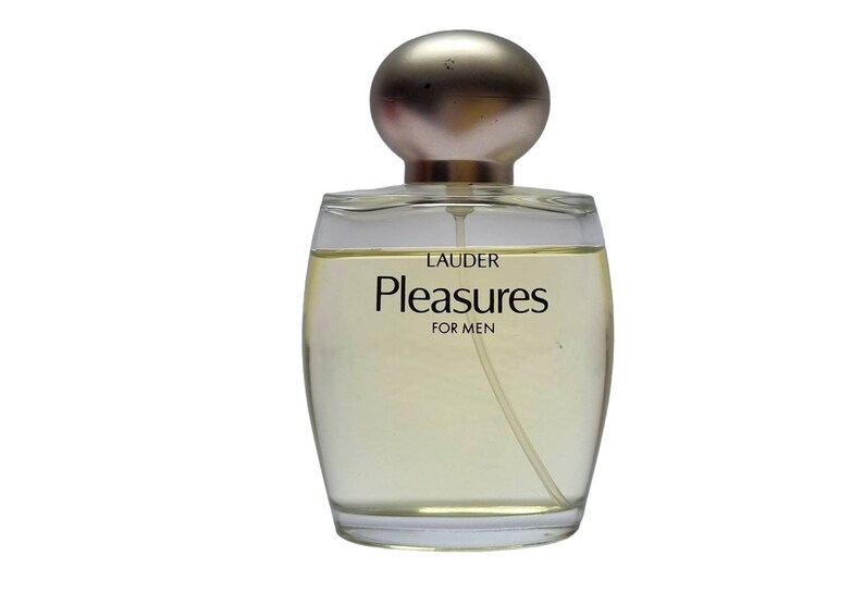 Może przedstawiać: Przezroczysta szklana butelka perfum z złotą zakrętką. Na etykiecie widnieje napis "LAUDER Pleasures FOR MEN".