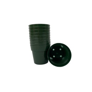May include: A stack of dark green plastic plant pots, with one pot lying on its side. The pots are cylindrical with a slightly flared rim and drainage holes in the bottom. The pots are empty and ready for planting.