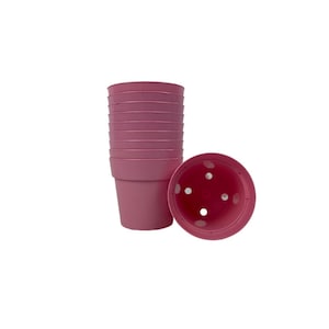 May include: A stack of pink plastic plant pots with drainage holes. The pots are stacked in a tower with one pot laying on its side.