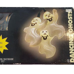 May include: A black rectangular box containing a set of 10 indoor/outdoor light set with ghost-shaped covers. The packaging features the text DANCING GHOSTS and a yellow starburst graphic with the text Meets New UL Standards! The ghosts are white.