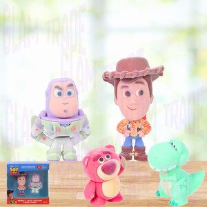 Może przedstawiać: Kolekcja figurek postaci z Toy Story, w tym Woody, Buzz Lightyear, Lotso i Rex. Figurki są w jasnych kolorach i stoją na drewnianej powierzchni. Obecny jest r&oacute;wnież zestaw w pudełku figurek Woody'ego i Buzza Lightyeara.