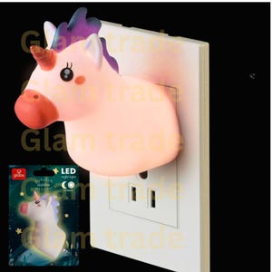 May include: A pink unicorn night light plugged into a white electrical outlet. The unicorn has a brown horn, purple and white mane, and a red nose. A product package with a unicorn graphic is visible.
