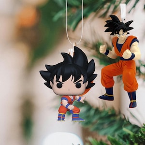 May include: Two Dragon Ball Z ornaments, one is a small figurine of Goku with black hair and a red and blue outfit, the other is a larger figurine of Goku with black hair and an orange outfit.
