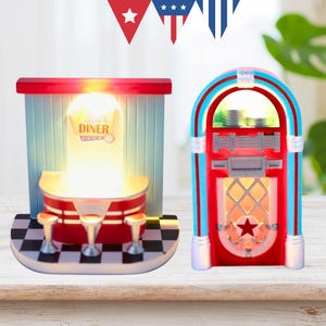 May include: Two retro-style decorative lights. One is a diner scene with a red and white counter, stools, and the text "Star Diner". The other is a red, blue, and white jukebox with a star design. Both lights are illuminated.