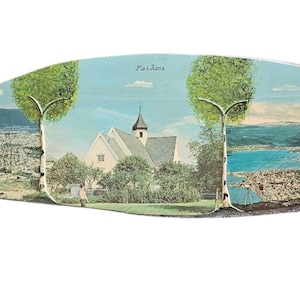 May include: A postcard depicting a church with a white facade and a steeple, surrounded by trees. The postcard is titled "No i Rama" and shows a view of a town with a lake in the background.