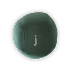 Pastel green inside of fabric storage basket with white letter j on the bottom of the box.