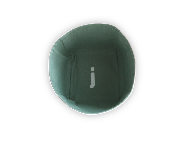 Pastel green inside of fabric storage basket with white letter j on the bottom of the box.