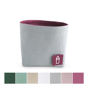 Front view of grey fabric storage basket with mulberry pink inside and square label with white clipart of milk bottle. Underneath seven squares with fabric colours: dark green, pastel green, beige, white, light grey, pastel rose and mulberry pink.