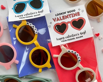 May include: A selection of children's sunglasses in shades like yellow, pink, and green. Each pair is packaged with a Valentine's Day card. The cards read "You Make My Day So Bright" or "Lookin' Good Valentine". Some sunglasses have names on the frames.