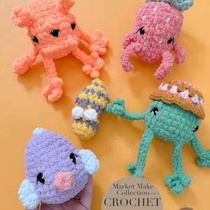 May include: Five handmade crochet amigurumi toys in various colours. The collection includes an orange crab, a pink strawberry, a green frog, a purple bird, and a small yellow and grey mushroom. The image also includes text that says "Market Make Collection Vol. 1 CROCHET PATTERN 5 in 1 NO SEW."