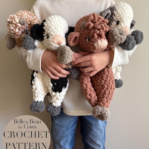 May include: A child holds four crocheted cow plushies. The cows are brown, white and black, and gray. The plushies are made with a chunky yarn and have large, round eyes. The plushies are part of a crochet pattern called "Belle & Beau the Cows Crochet Pattern".