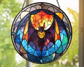 May include: A round stained glass window hanging featuring a bat with outstretched wings. The bat is purple with a yellow chest, set against a colorful background of orange, yellow, blue, and purple. The window is framed in black.