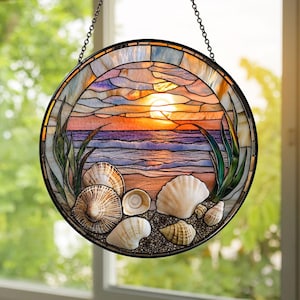 May include: Round stained glass window panel depicting a sunset over the ocean, with seashells and sea grass. The panel features a black metal frame and a hanging chain. The sunset is rendered in shades of orange, pink, and purple.