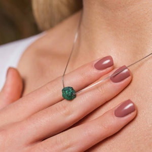 May include: A silver chain necklace with a green malachite stone pendant. The stone is a rough, natural shape.