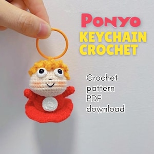 May include: A handmade crochet keychain featuring a character with orange hair, large eyes, and a red dress. The keychain is attached to an orange ring. Text on the image reads "PONYO KEYCHAIN CROCHET" and "Crochet pattern PDF download."