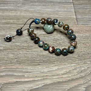 May include: A bracelet made of brown, blue, and white patterned beads with a black cord.