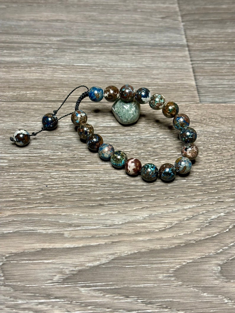May include: A bracelet made of brown, blue, and white patterned beads with a black cord.