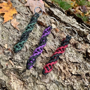Puede incluir: Tres llaveros trenzados con paracord negro, verde y rojo. Cada llavero tiene un anillo de llave plateado.
