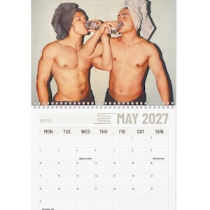 May include: A calendar featuring a photograph of two shirtless individuals drinking from cans, with towels on their heads. The calendar is dated May 2027, with the days of the week and dates clearly visible. The calendar also includes the holidays Cinco de Mayo, Mother's Day, and Memorial Day.