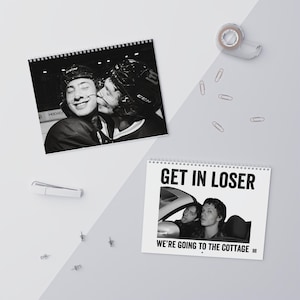 Op de afbeelding: Twee spiraalgebonden wandkalenders met zwart-witfoto's. De ene kalender toont twee hockeyspelers met helmen, de andere toont twee personen in een auto met de tekst GET IN LOSER WE'RE GOING TO THE COTTAGE.