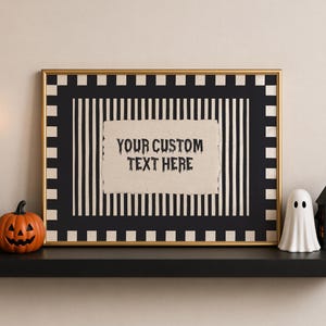 May include: A rectangular wall art print in a gold frame featuring a black and white striped background with a checkered border. The center displays a beige paper-like rectangle with the black text YOUR CUSTOM TEXT HERE in a spooky font.