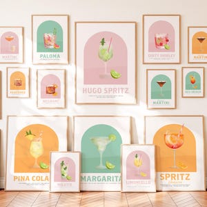 May include: A collection of framed wall art prints featuring various cocktail illustrations. Each print displays a specific drink name, such as Hugo Spritz, Margarita, and Pina Colada, set against a pastel-coloured arched background.