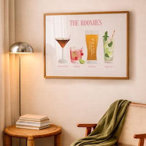 May include: A framed wall art print titled THE ROOMIES featuring four illustrated drinks labeled Hannah, Nina, Jenna, and Naomi. The artwork displays a martini, a cocktail with cherries and lime, a beer glass labeled Michelob ULTRA, and a mojito.