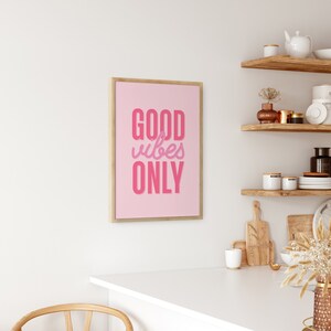 May include: A framed pink poster with the text "GOOD vibes ONLY" in a pink and purple gradient.