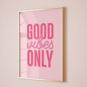 May include: A gold framed pink poster with the text "GOOD vibes ONLY" in pink lettering.