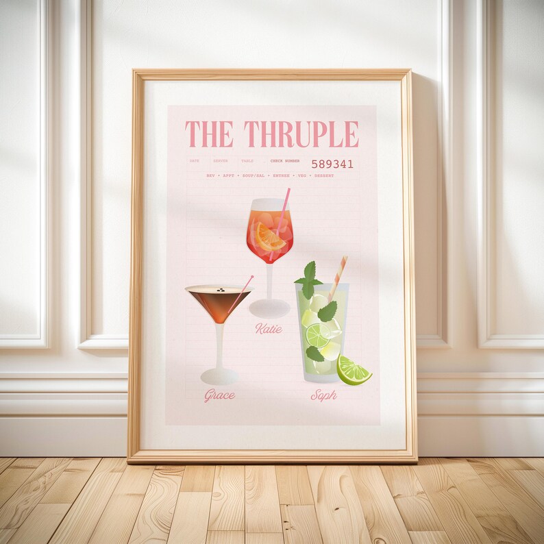 Op de afbeelding: Een ingelijste print met drie cocktailillustraties op een roze achtergrond. De print leest "THE THRUPLE" bovenaan. De cocktails zijn een oranje drankje, een martini en een mojito, elk met een naam eronder.