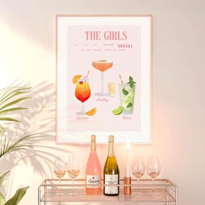 Op de afbeelding: Een ingelijste print getiteld "The Girls" met illustraties van cocktails en namen. Daaronder een bartrol met twee flessen mousserende wijn, een brandende kaars en wijnglazen. De print en de kar staan tegen een lichtroze muur.