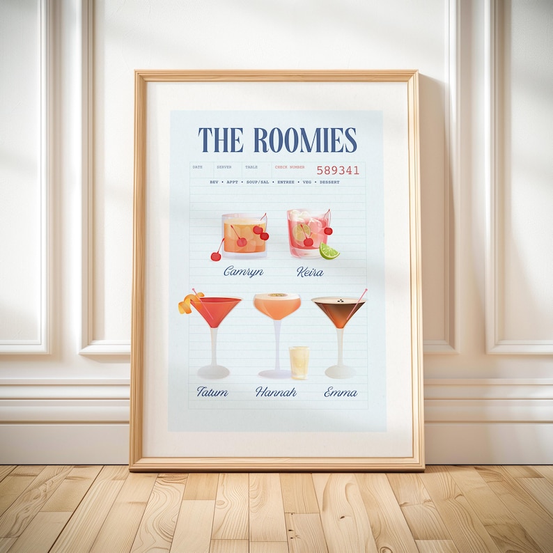 Op de afbeelding: Een ingelijste print getiteld "THE ROOMIES" met cocktailillustraties. De print toont zes cocktailglazen met diverse garneringen en namen onder elk drankje. De achtergrond is lichtblauw met lijnen en de lijst is lichtbruin.