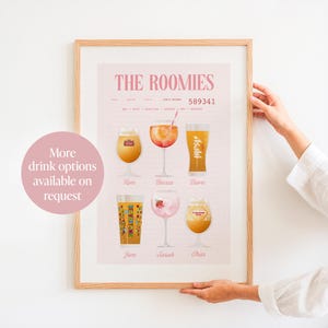 Op de afbeelding: Een ingelijste print met de titel "THE ROOMIES" met illustraties van verschillende drankjes, waaronder bier en cocktails. De print heeft een roze achtergrond en bevat de namen Tom, Becca, Dave, Jem, Sarah en Char. De tekst "More drink options available on request" is ook zichtbaar.